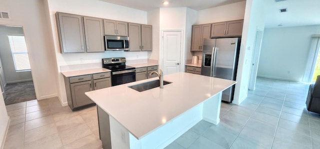 kitchen featuring stainless steel appliances, light tile patterned floors, sink, and a kitchen island with sink