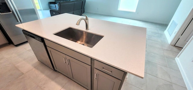 kitchen with sink, light tile patterned floors, an island with sink, gray cabinetry, and appliances with stainless steel finishes