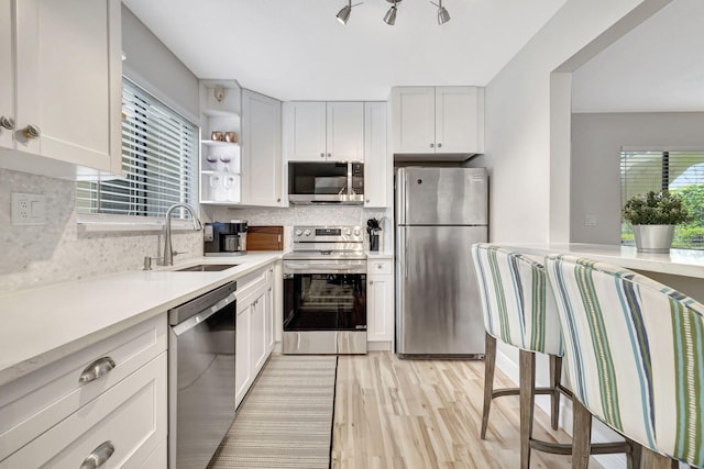 kitchen featuring white cabinetry, light wood-type flooring, stainless steel appliances, and sink