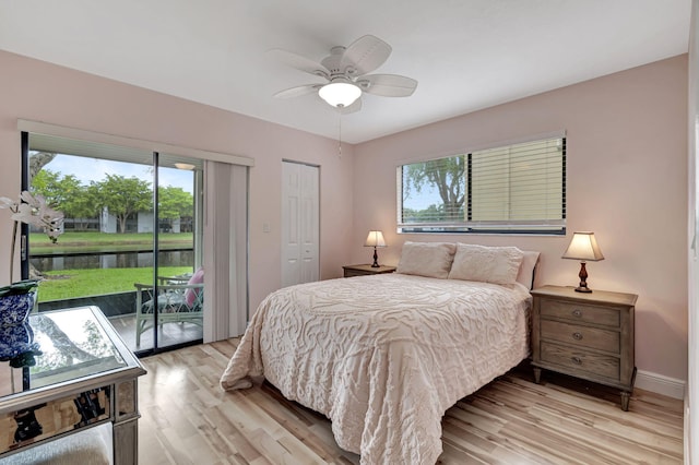 bedroom with a water view, ceiling fan, light hardwood / wood-style flooring, a closet, and access to outside