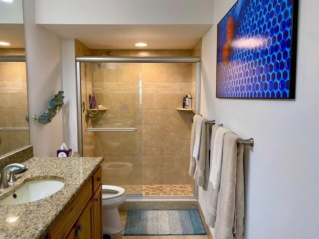 bathroom with toilet, vanity, tile patterned floors, and a shower with shower door