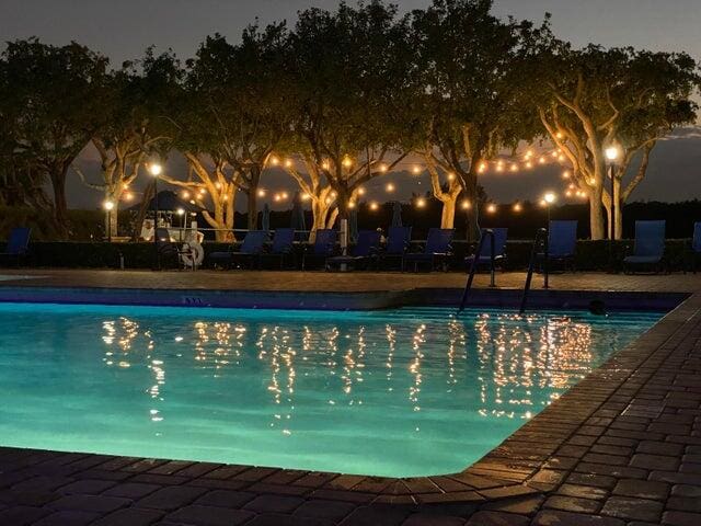 pool at night featuring a patio