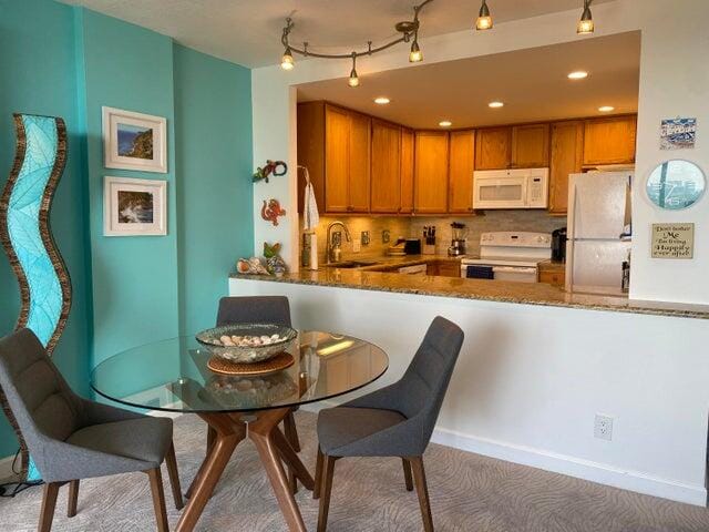 kitchen featuring white appliances, sink, kitchen peninsula, and carpet floors