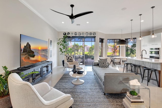 living room featuring ceiling fan, ornamental molding, and sink