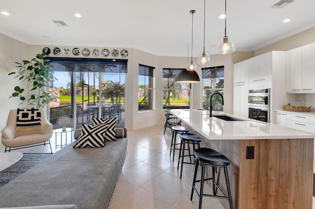 kitchen with white cabinetry, sink, double oven, a spacious island, and decorative light fixtures