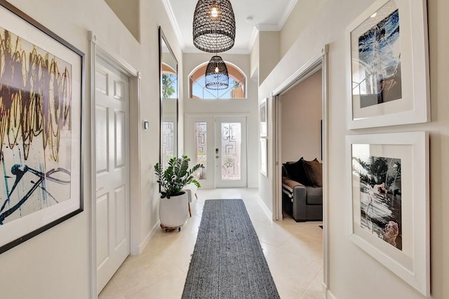 tiled entryway featuring crown molding and a notable chandelier