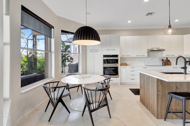 kitchen featuring white cabinetry, sink, stainless steel double oven, and decorative light fixtures