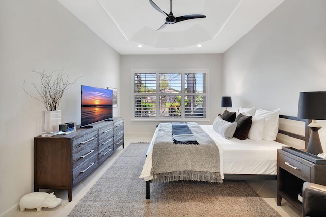 tiled bedroom with a tray ceiling and ceiling fan