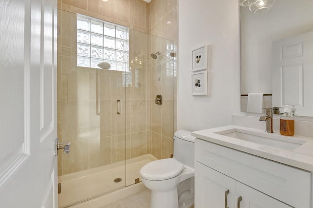 bathroom featuring vanity, toilet, and a shower with shower door