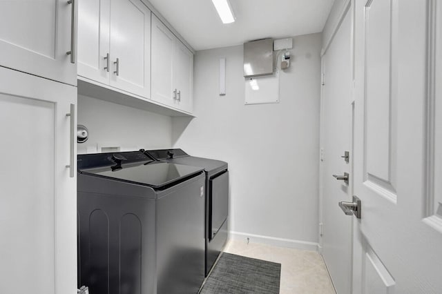 washroom with light tile patterned floors, cabinets, and washer and dryer