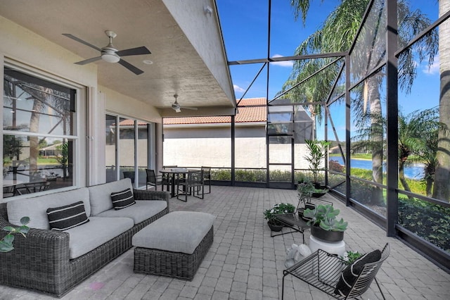 view of patio featuring a water view, ceiling fan, and a lanai