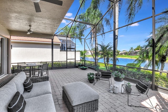 view of patio / terrace with a water view, glass enclosure, and ceiling fan