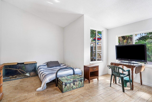 bedroom featuring a textured ceiling, light wood-type flooring, and lofted ceiling