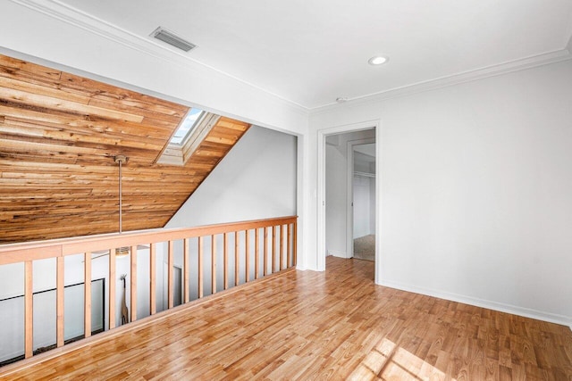 unfurnished room with vaulted ceiling with skylight, wood ceiling, crown molding, and light hardwood / wood-style flooring