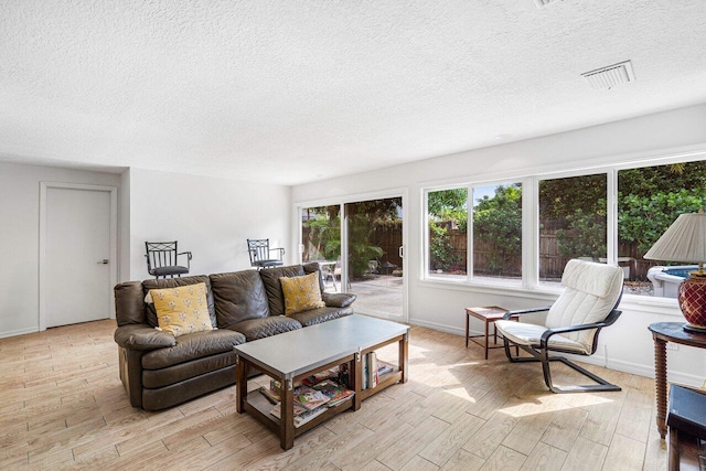 living room with a textured ceiling and light wood-type flooring