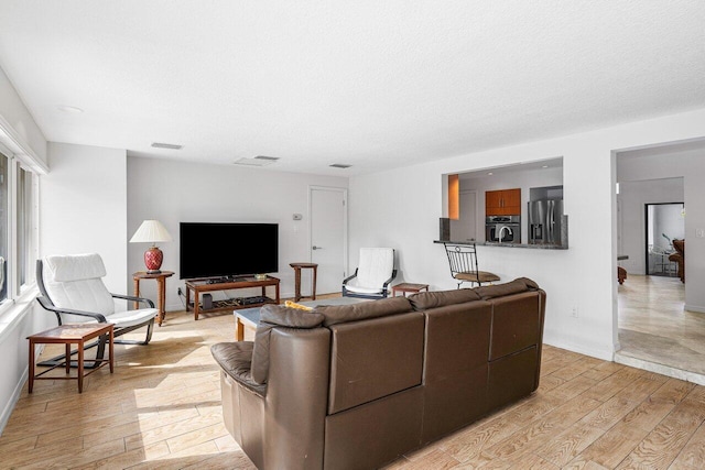 living room with a textured ceiling and light wood-type flooring