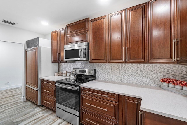 kitchen with backsplash, light wood-type flooring, and appliances with stainless steel finishes