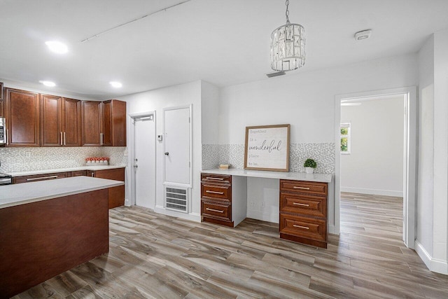 kitchen featuring backsplash, light wood-type flooring, hanging light fixtures, and stainless steel appliances