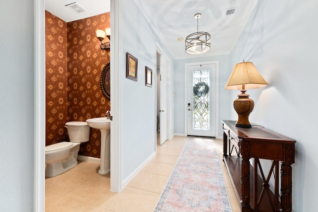 entryway with light tile patterned floors, an inviting chandelier, and ornamental molding