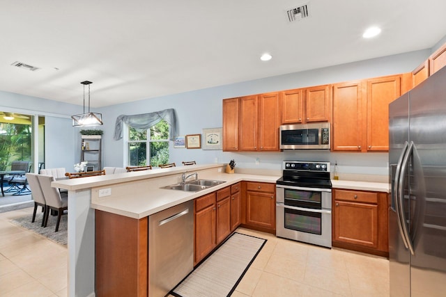 kitchen with stainless steel appliances, kitchen peninsula, sink, light tile patterned floors, and pendant lighting