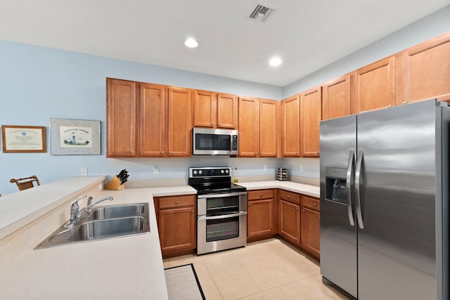 kitchen with appliances with stainless steel finishes, sink, and light tile patterned flooring