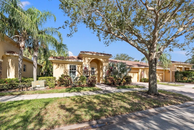 mediterranean / spanish-style home featuring a garage and a front yard