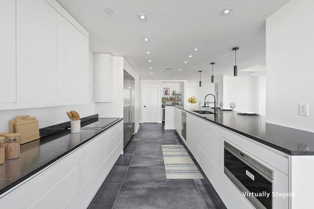 kitchen with white cabinetry, sink, beverage cooler, and hanging light fixtures