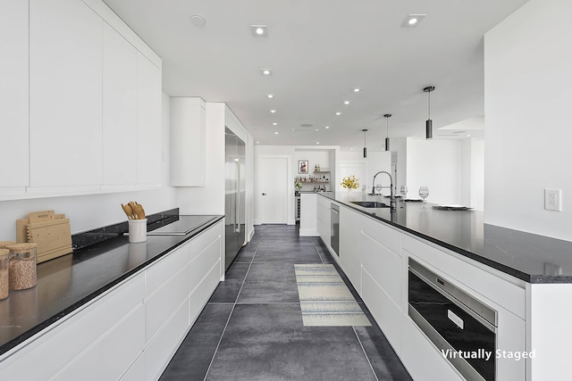 kitchen with pendant lighting, white cabinets, a sink, and modern cabinets