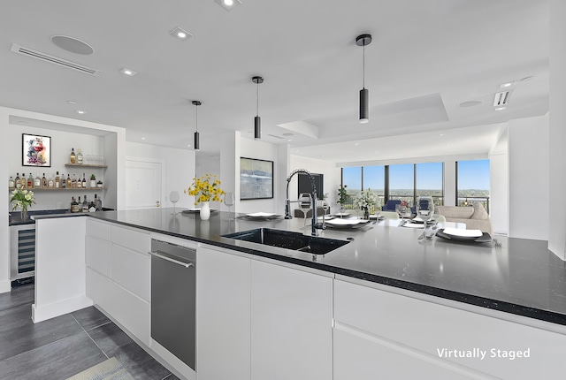 kitchen featuring modern cabinets, a sink, white cabinetry, and decorative light fixtures