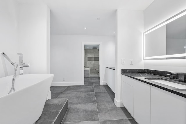 bathroom featuring a stall shower, a freestanding tub, vanity, and baseboards