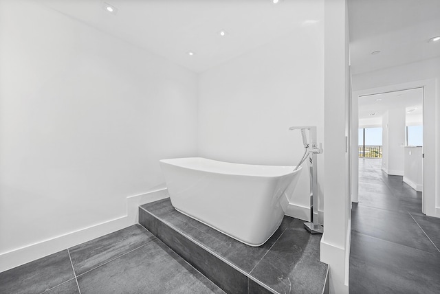 full bathroom with recessed lighting, a soaking tub, and baseboards