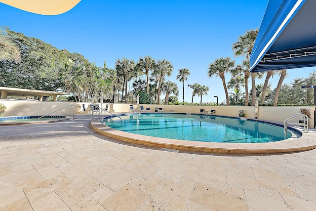 pool with a patio area and fence