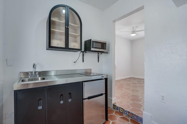 kitchen featuring sink, stainless steel counters, light tile patterned flooring, ceiling fan, and appliances with stainless steel finishes