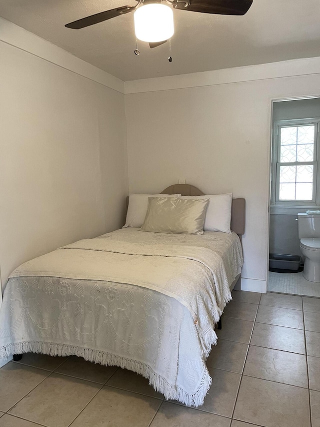 tiled bedroom featuring ceiling fan and connected bathroom