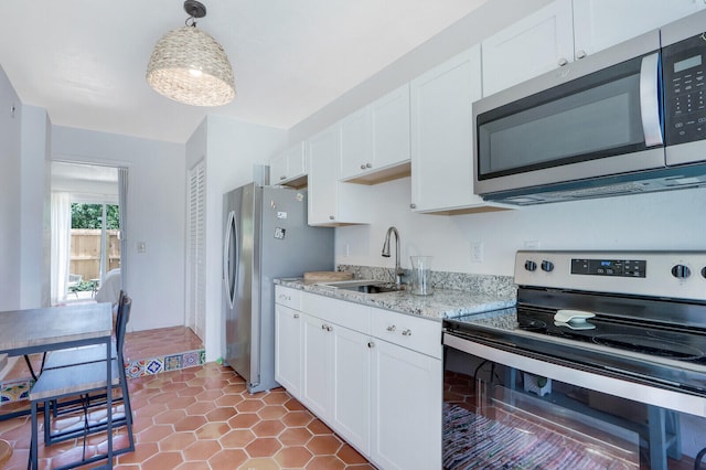 kitchen featuring appliances with stainless steel finishes, pendant lighting, white cabinetry, and sink