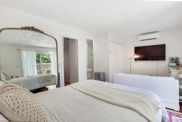 bedroom featuring an AC wall unit, a textured ceiling, and ensuite bath