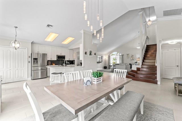 dining space with crown molding, light tile patterned floors, a chandelier, and high vaulted ceiling