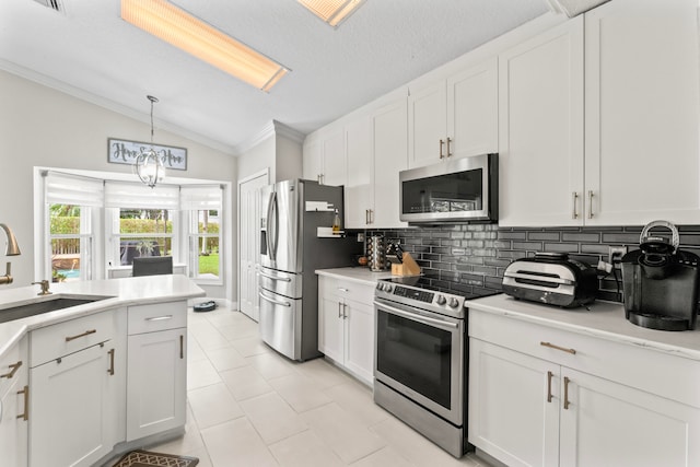 kitchen with white cabinets, stainless steel appliances, vaulted ceiling, and sink