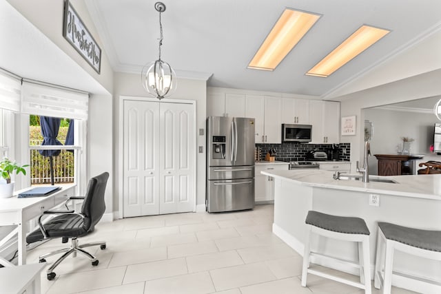 kitchen with sink, light stone counters, lofted ceiling, white cabinets, and appliances with stainless steel finishes