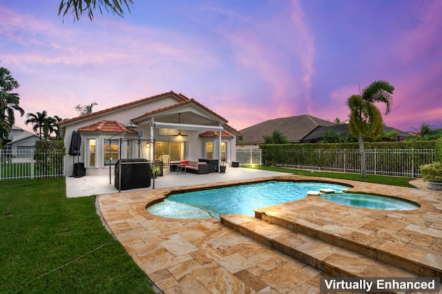 pool at dusk with an in ground hot tub, a yard, an outdoor hangout area, and a patio area