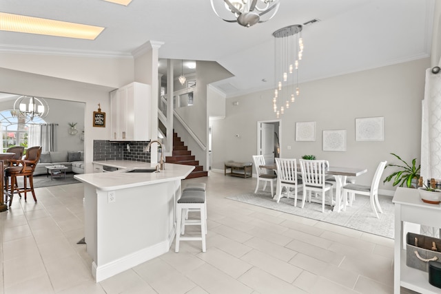 kitchen with lofted ceiling, white cabinets, sink, decorative light fixtures, and kitchen peninsula