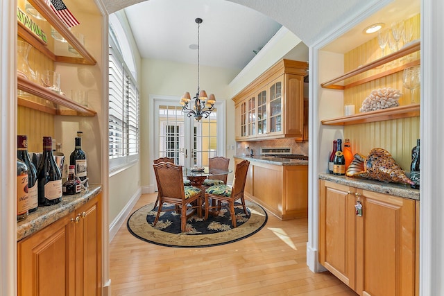 dining space featuring plenty of natural light, light hardwood / wood-style floors, french doors, and an inviting chandelier