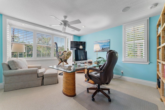 carpeted office space featuring ceiling fan and a textured ceiling