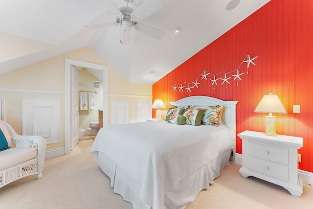 bedroom with ensuite bath, ceiling fan, light carpet, and vaulted ceiling