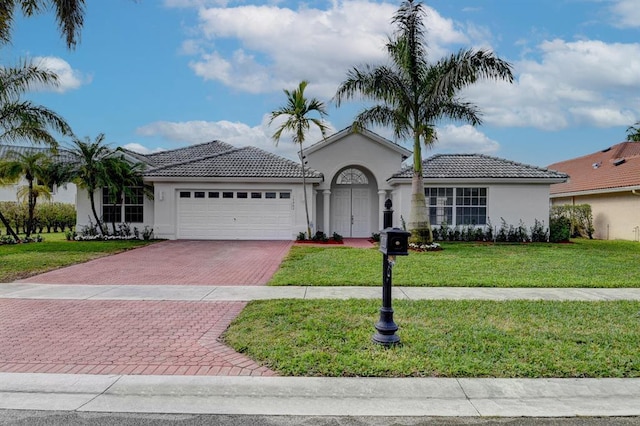 mediterranean / spanish home with a garage and a front lawn