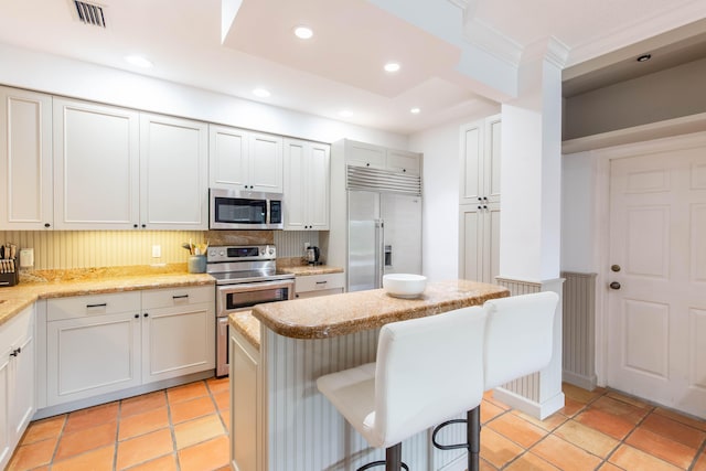 kitchen with light stone counters, a center island, a breakfast bar, backsplash, and appliances with stainless steel finishes