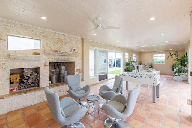 tiled living room with ceiling fan and a large fireplace