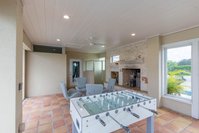 playroom with a fireplace, light tile patterned flooring, and ceiling fan