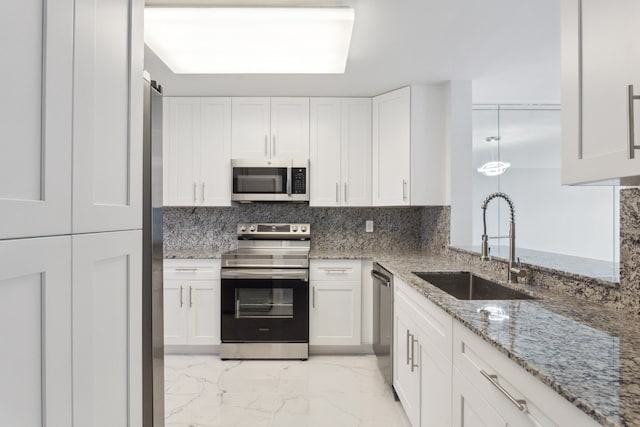 kitchen featuring white cabinets, stainless steel appliances, light stone counters, and sink