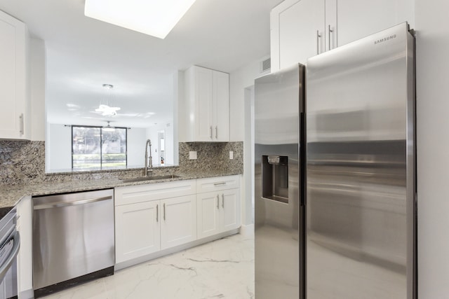 kitchen featuring light stone countertops, sink, stainless steel appliances, tasteful backsplash, and white cabinets